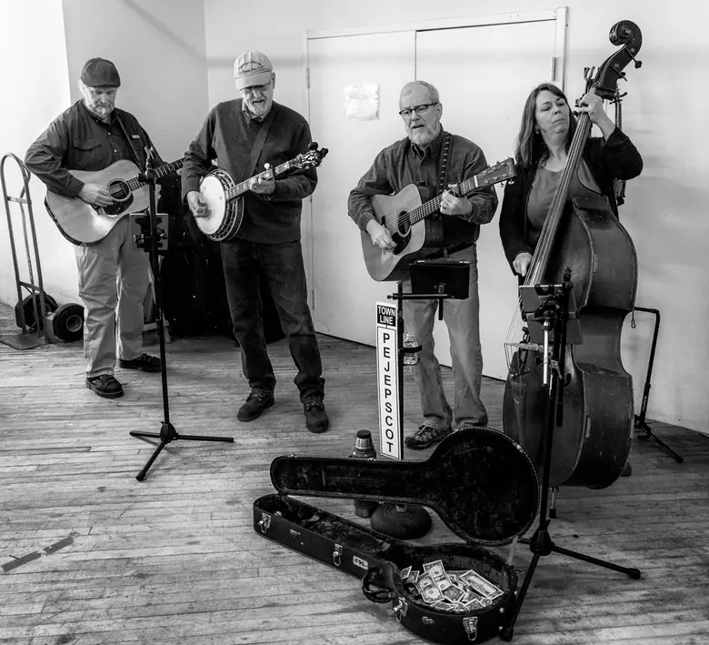 Black-and-white photo of a four-piece string band playing at an indoor farmers market in Brunswick, Maine